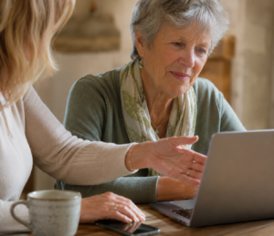 Older woman receiving friendly one-to-one computer help at home